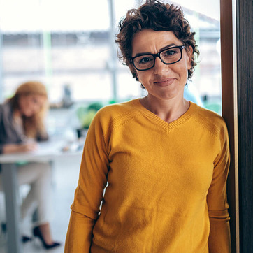 Frau mit Brille lehnt an Wand und macht sich Gedanken über Tipps für gesunde Augen.