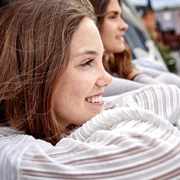 Junge Frauen schauen lächelnd von Balkon