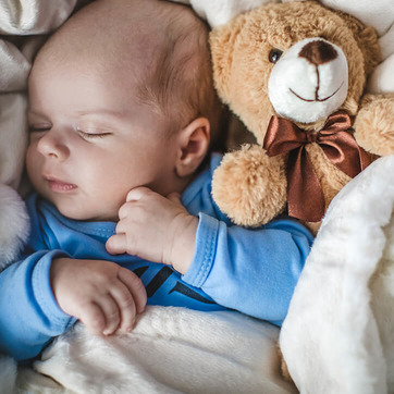 Baby schläft neben Teddy