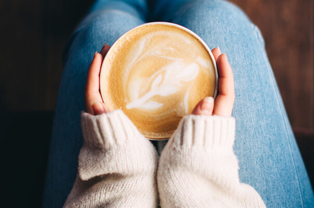 Frau hält Milchkaffee auf dem Schoss